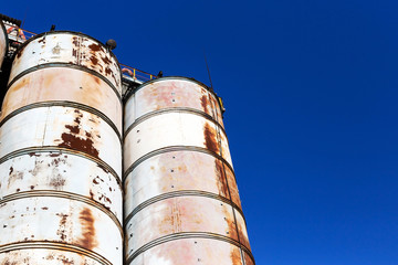 Old, abandoned concrete plant with iron rusty tanks and metal structures. The crisis, the fall of the economy, stop production capacity led to the collapse. Global catastrophe.