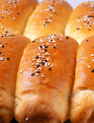 Yeast hot dog buns sprinkled with sesame seeds right from the oven. Food background with freshly baked product