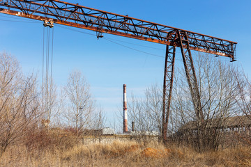 Old, rusty gantry crane on railroad, an abandoned concrete plant. Crisis, collapse of economy, and shutdown of production capacities have led to collapse. Global catastrophe. 