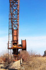 Old, rusty gantry crane on railroad, an abandoned concrete plant. Crisis, collapse of economy, and shutdown of production capacities have led to collapse. Global catastrophe. 