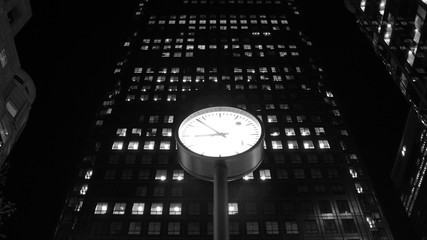 Illuminated clock in front of skyscraper
