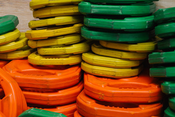 Dumbbells of different sizes. dumbbells in the fitness room. Dumbbells of orange, green and yellow.