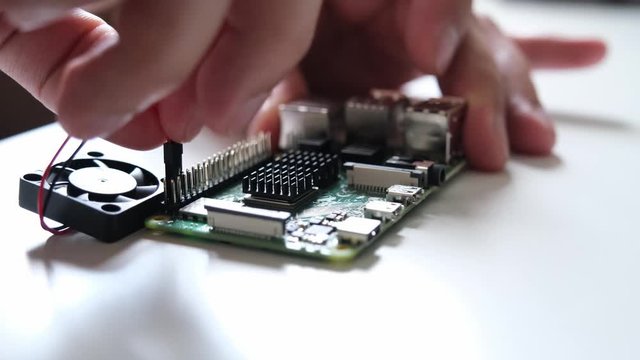 Close-up of male hands connecting a little fan to a ARM single board computer. Technology concept.