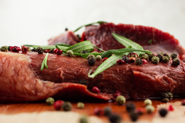 raw beef steak with vegetables, seasoned with pepper and rosemary, close-up