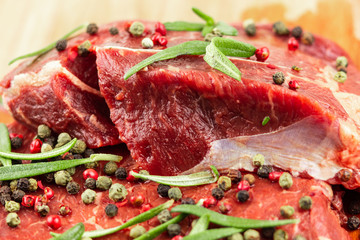 raw beef steak with vegetables, seasoned with pepper and rosemary, close-up