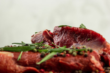 raw beef steak with vegetables, seasoned with pepper and rosemary, close-up