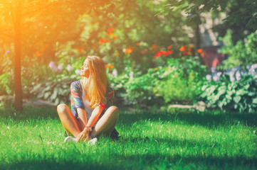 Happy free young woman sitting outdoors in yoga position with closed eyes on summer park grass Calm girl enjoy smile and relax in spring city air. Mindset inner light peace concept. Bali asia sun joy