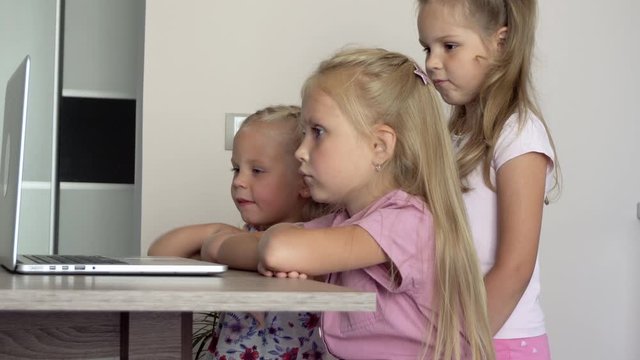 Distance learning children. Three preschool girls with a computer at home. Children and technology