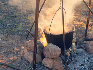 Early sunny morning. Food is cooked in pot on the bonfire during hike.
