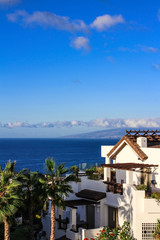 White house in colors, against the ocean, blue sky and La Gomera island