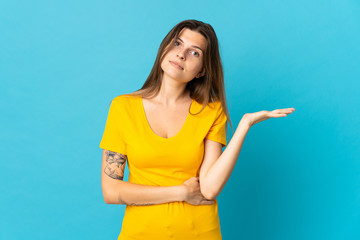 Young slovak woman isolated on blue background having doubts