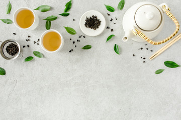 Herbal tea with two white tea cups and teapot, with green tea leaves. Flat lay, top view. Tea...