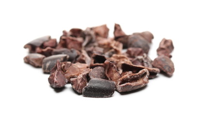Chopped up cocoa pieces pile, isolated on white background, closeup