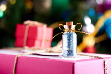 Small glass bottle with glitter on xmas gifts background