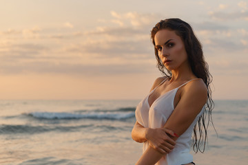 Fototapeta na wymiar Sexy woman posing on beach near the sea at sunrise