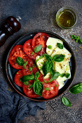 Caprese - traditional italian tomato salad with mozzarella cheese and basil. Top view with copy space.