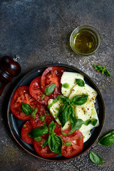 Caprese - traditional italian tomato salad with mozzarella cheese and basil. Top view with copy space.