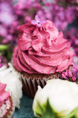 Pink cupcake with white rose and lilac on table