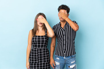 Teenager caucasian couple isolated on blue background covering eyes by hands. Do not want to see something