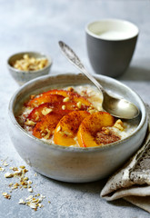 Delicious oat porridge with caramelized peaches and nuts for a breakfast.