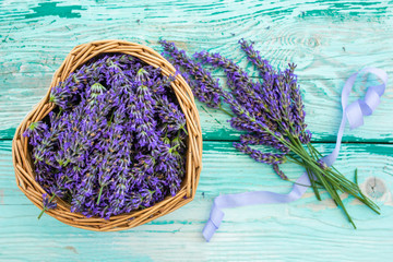 Lavender flowers in a heart-shaped basket on a wooden background.