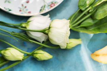 Obraz na płótnie Canvas White roses on blue table near tea