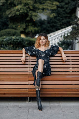 fashion look. walking woman in dress and boots outdoor in city in summer