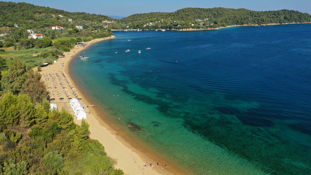 Aerial drone photo of famous organised with sun beds and umbrellas sandy beach of Agia Paraskevi in island of Skiathos, Sporades, Greece