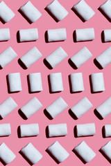 White marshmallows turning in different sides on a pink background. Pattern with hard shadows