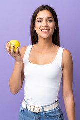 Young caucasian woman isolated on purple background with an apple