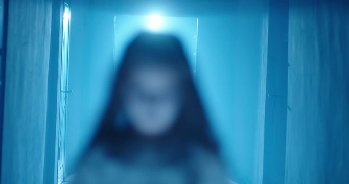 Demonic psycho child in cursed house. Little girl, dressed in halloween ghost party costume in sundress scarily staring at camera 4k footage