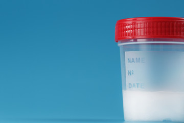 A container for biomaterials with sperm analysis and a red lid on a blue background.