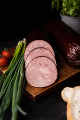  Sliced dry smoked sausage on a cutting board, focus on slices.
