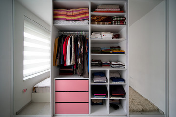 Oragniyed and tidied wardrobe with clothes in a bedroom