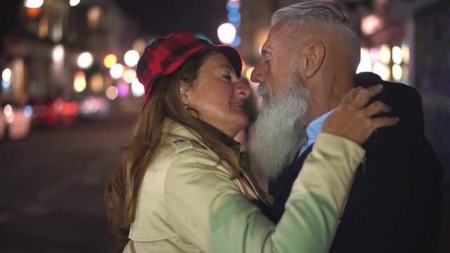 Senior couple kissing outdoor at night time on city street - Slow Motion