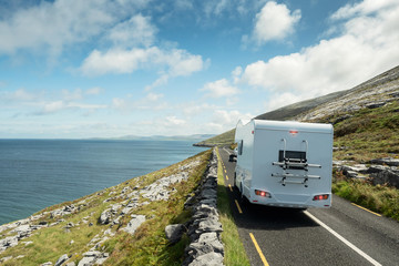 Motor home driving on a small asphalt road by blue ocean with beautiful view on Galway bay and surrounding landscape., Magnificent Burren National Geo park, Ireland. Warm sunny day. 