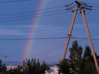 rainbow over the city on the background of wires and poles