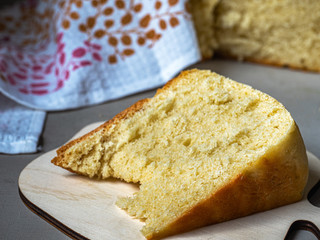 Homemade white flour bread under a linen towel on a wooden table