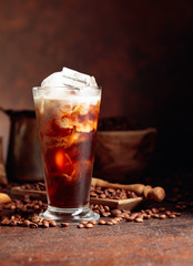 Ice coffee with cream being poured into it showing the texture and refreshing look of the drink.