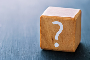 A question mark is printed on a wooden block, the concept of thinking, doubting and looking for an...