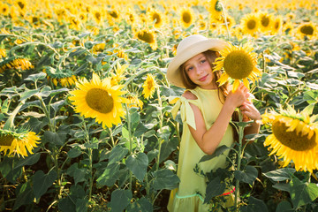 beautiful young teenage girl in hat in a field of sunflowers in summer