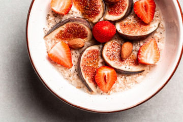 healthy Breakfast oatmeal with figs, strawberries and almonds on a white table. vegan food, Gluten free, lactose free, top view