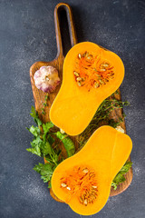 Butternut squash on the black table. Half cutted pumpkin squash with spices for cooking, top view copy space