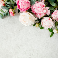 Beautiful pink peony flowers on gray stone table with copy space for your text. Flat style, top view