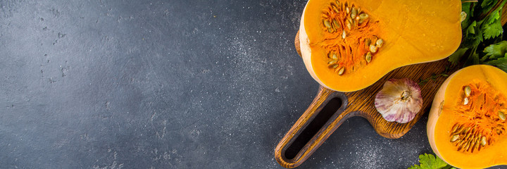 Butternut squash on the black table. Half cutted pumpkin squash with spices for cooking, top view copy space