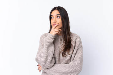 Young brunette woman over isolated white background having doubts and with confuse face expression