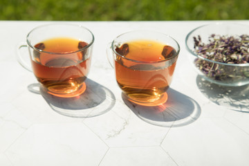 Chamaenerion angustifolium tea (Cypress, pink willow, Ivan tea) with dry and fresh flowers for decoration in two glass cups on a light background. Concept of herbal medicine. Horizontal orientation