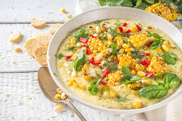 Homemade autumn classic corn cream soup with grilled corn, herbs and croutons, copy space