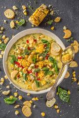 Homemade autumn classic corn cream soup with grilled corn, herbs and croutons, copy space