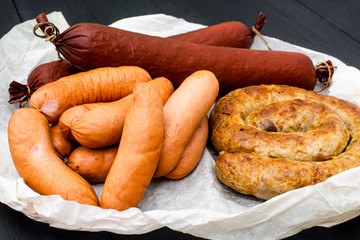 Different types of natural sausages on a wooden background.